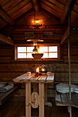 Gegenüberliegende Sitzbänke am Tisch unter dem Fenster in Jagdhütte, Svartadalen, Schweden
