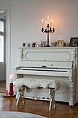 Kerzen auf einem weiß gestrichenen Klavier in einer Stockholmer Wohnung aus dem 20. Jahrhundert