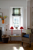 Matching red lamps at sunlit window of Devon living room