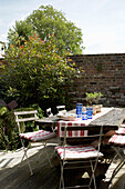 Tisch und Klappstühle in einem ummauerten Garten in Rye, Sussex