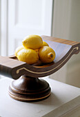 Detailaufnahme einer hölzernen Schale mit Zitronen auf einer Fensterbank