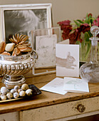 Decanter and silverware bowl and photographs on wooden side table with drawers