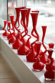 Rote Designervasen in einer Reihe auf der Fensterbank