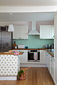 Pendant lights hang over wallpapered kitchen island