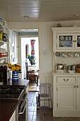 Cremefarbener Küchenschrank und gefliester Boden mit Blick in ein sonnendurchflutetes Zimmer