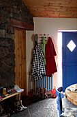 Coats hang above radiator in kitchen with exposed stone wall