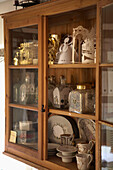 Glass and hold ornaments in wooden glass-fronted cabinet