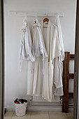 Weiße Morgenmäntel und Wäschesäcke an Garderobenleiste aus Holz