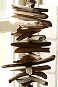 Driftwood mobile hanging in window of beach house in Norfolk, UK