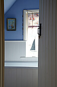 Blick durch die Tür in Badezimmer eines Strandhauses mit blau gestrichenen Wänden, Norfolk, UK