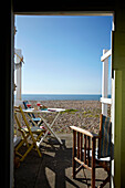 Blick durch die Tür einer Strandhütte auf den Kieselstrand an der Küste von West Sussex, England, UK