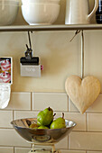 Heart shaped ornament and pears on kitchen scales in Brighton home, East Sussex, England, UK