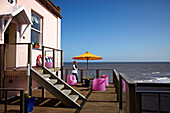 Frau auf der Balkonterrasse eines Strandhauses in Cromer, Norfolk, UK