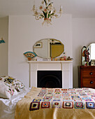 Doppelbett mit gehäkelter Tagesdecke vor dem Kamin in einem Schlafzimmer im traditionellen Stil