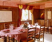 A large traditional dining room with a large chequered table cloth covered wood dining table and chairs