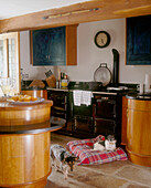 Two small dogs one on a tartan cushion in a traditional style wood based kitchen with a stone slab floor