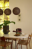 A modern dining room with black lampshades above a large oval dining table surrounded by traditional wooden chairs