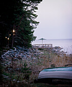 Path illuminated by lanterns leading to a raised platform area with an upturned boat in the foreground