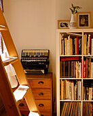 A detail of a modern sitting room shelving unit with books chest of drawers accordion step ladder
