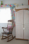 Detail of children room with a wardrobe with toys on it and wooden rocking chair