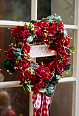A detail of a Christmas wreath of red roses set on an outside window