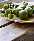 Green apples on wooden plate