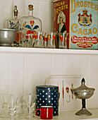 Ein Detail von verschiedenen Gegenständen auf Regalen, bemalten Gläsern und Flaschen und altmodischen Dosen