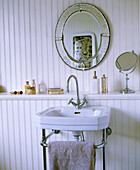 Venetian mirror above washbasin on steel stand against wood panelling