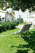 Deck chair on lawn set in shade under tree
