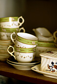 Detailaufnahme von dekorativen Teetassen und Untertassen in einem Regal
