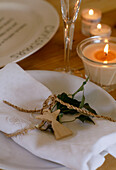 Gedeck dekoriert mit Holzengel, Blättern und Schnur daneben Kerzen in Gläsern