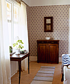 Wooden side table beneath window with curtains