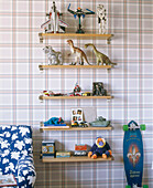 Toys arranged on a series of shelves mounted on a chequered patterned wall