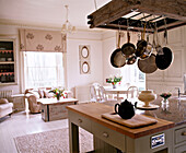 Töpfe hängen über der Arbeitsplatte in einer offenen Küche mit einer Teekanne auf einem Schneidebrett