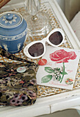 Grußkarte, Sonnenbrille und blauer Keramiktopf auf Nachttisch
