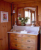 Swiss chalet bedroom with wood panelling and antique marble topped chest of drawers