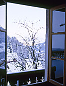 Blick aus dem Fenster eines schweizer Chalets auf schneebedeckte Berge