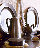 Pewter plates and coffee pot on shelf