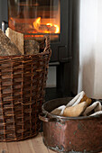 Logs in wicker basket in front of stove with lit fire