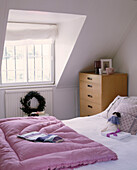 A modern bedroom with double bed chest of drawers pink quilt cover window