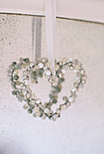 A detail of a beaded heart decorated hanging from ribbon