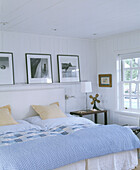 Fotografien auf einem Regal über einem Doppelbett mit blassblauem Bettbezug