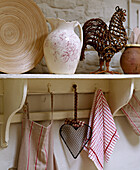 Ceramics on painted shelf with tea cloths on hooks