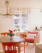 Country style dining room with a lamp suspended over a table surrounded by painted wooden chairs