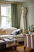 Gustavian clock and sofa at window with drinks tray in Port Issac beach house Cornwall