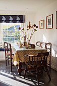 Wooden chairs at sunlit table with spotty tablecloth in Port Issac beach house Cornwall