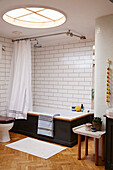 Large white tiled bathroom with skylight and parquet floor in Brighton home East Sussex, UK