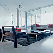 Sofas, Stühle und ein großer Couchtisch in einem modernen, offenen Wohnzimmer