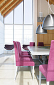 Dining room with antique oak table polished in grey with chair upholstered in violet courderoy with Italian lamp shades