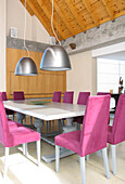 Dining room with antique oak table polished in grey with chair upholstered in violet courderoy with Italian lamp shades